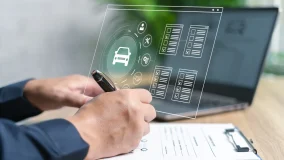 Insurance agent using laptop computer and paper documents to compare insurance rates