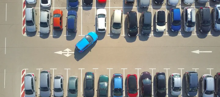 AERIAL TOP DOWN: Flying above bad driver incapable to park a car on parking space in big crowded parking lot. Female having problems, unable to park a car in parking spot. Parking fail on parkspace.