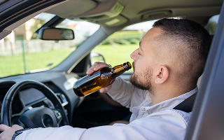Man drinking alcohol while driving a car.