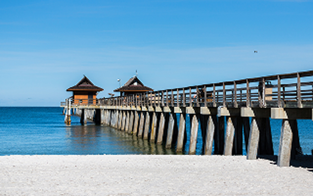 Naples, Florida Pier Extending from White Sand Beach on a Clear Summer Day – Naples, cheap car insurance in Florida