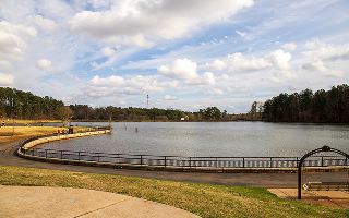 A gorgeous winter landscape at Rhodes Jordan Park with a blue lake, yellow winter grass lush green trees, people walking and blue sky with powerful clouds at sunset in Lawrenceville Georgia USA – Lawrenceville, cheap car insurance in Georgia