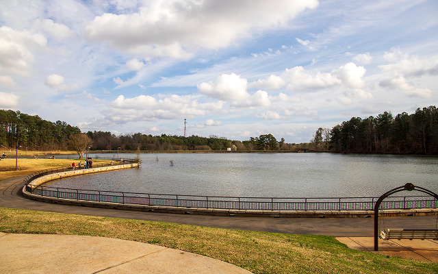 A gorgeous winter landscape at Rhodes Jordan Park with a blue lake, yellow winter grass lush green trees, people walking and blue sky with powerful clouds at sunset in Lawrenceville Georgia USA – Lawrenceville, cheap car insurance in Georgia